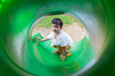 Küçük Asyalı çocuk oyun alanında summ, slayt yukarı tırmanma