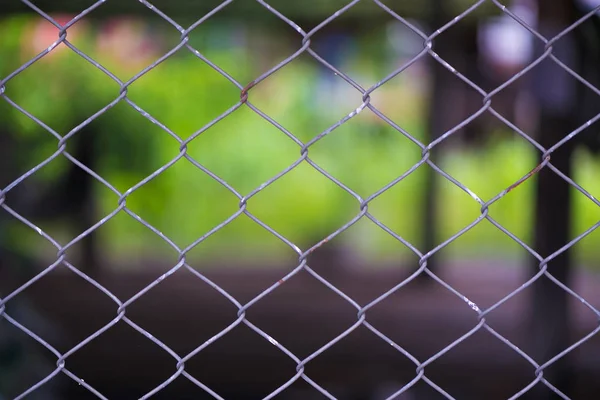 Verroeste ketting Link hek van staal verrekening op wazig achtergrond. — Stockfoto