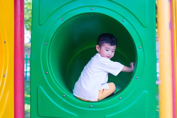 Lindo asiático chico jugando y sonriendo en amarillo túnel en el playg — Foto de Stock