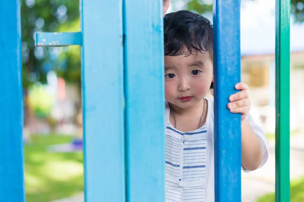 Sad Asian kid behind the grid trying to escape. shallow DOF — Stock Photo, Image