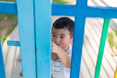 Üzgün Asyalı çocuk kaçmaya çalışırken ızgara arkasında. sığ Dof