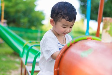 Genç Asyalı çocuk oyun bahçesi und sallanan bir demir tren