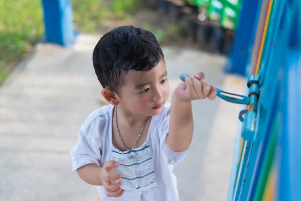 Sad Asian kid behind the grid trying to escape. shallow DOF — Stock Photo, Image
