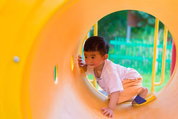 Leuke Aziatische jongen spelen en lachend in gele tunnel op de playg — Stockfoto