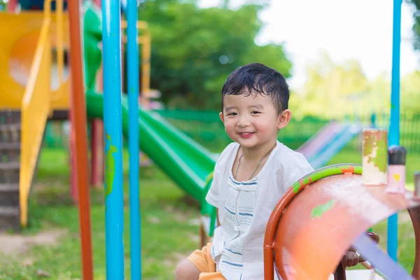 Young Asian boy play a iron train swinging at the playground und — Stock Photo, Image