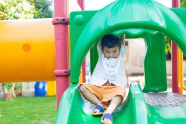 Küçük Asyalı Çocuk Bahçesi sunli altında slayt oynayan