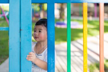Üzgün Asyalı çocuk kaçmaya çalışırken ızgara arkasında. sığ Dof