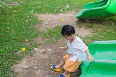 Küçük Asyalı Çocuk Bahçesi sunli altında slayt oynayan