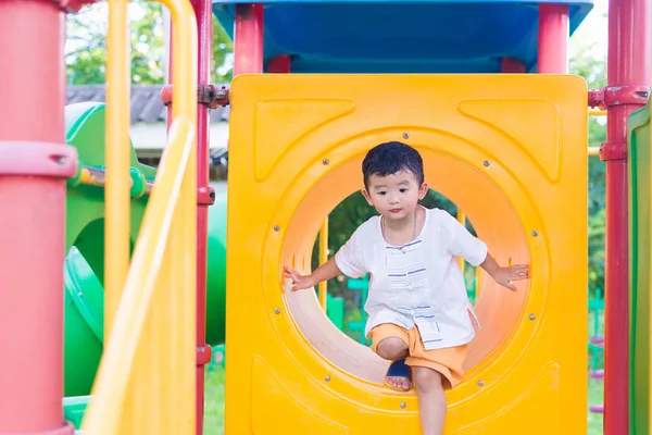 Lindo asiático chico jugando y sonriendo en amarillo túnel en el playg — Foto de Stock