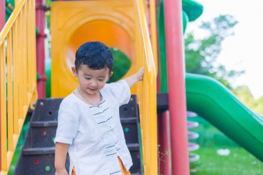 Asyalı çocuk parkta merdivenlerden aşağı gider.