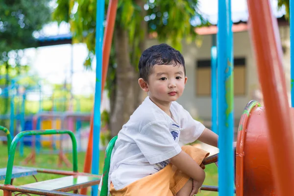 Genç Asyalı çocuk oyun bahçesi und sallanan bir demir tren