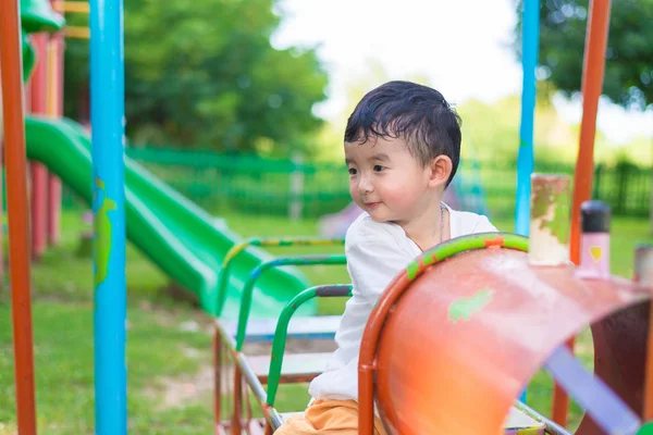 Young Asian boy play a iron train swinging at the playground und — Stock Photo, Image