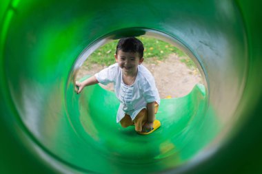 Küçük Asyalı çocuk oyun alanında summ, slayt yukarı tırmanma