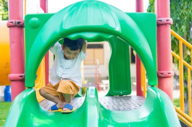 Küçük Asyalı Çocuk Bahçesi sunli altında slayt oynayan