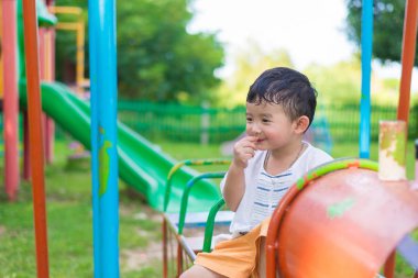 Genç Asyalı çocuk oyun bahçesi und sallanan bir demir tren