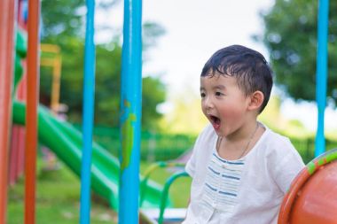 Genç Asyalı çocuk oyun bahçesi und sallanan bir demir tren