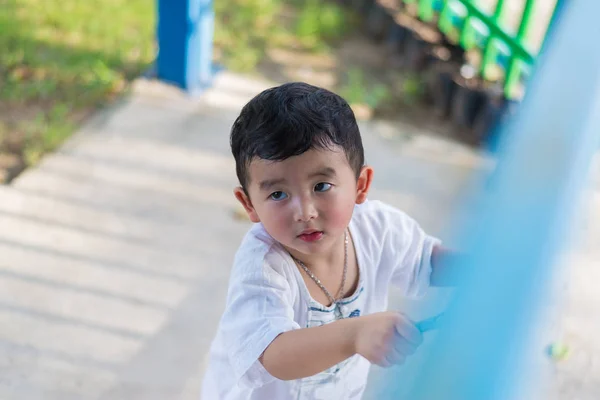 Sad Asian kid behind the grid trying to escape. shallow DOF — Stock Photo, Image