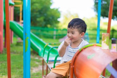 Genç Asyalı çocuk oyun bahçesi und sallanan bir demir tren