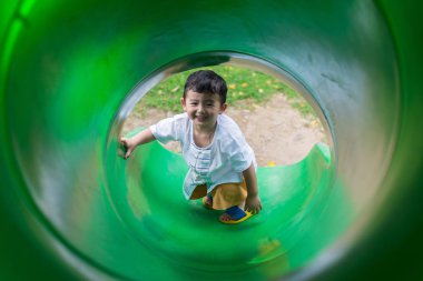 Küçük Asyalı çocuk oyun alanında summ, slayt yukarı tırmanma
