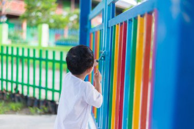 Üzgün Asyalı çocuk kaçmaya çalışırken ızgara arkasında. sığ Dof