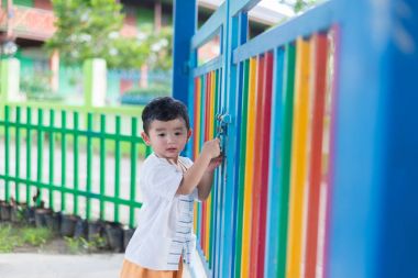 Üzgün Asyalı çocuk kaçmaya çalışırken ızgara arkasında. sığ Dof