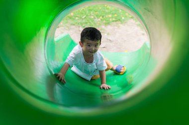 Küçük Asyalı çocuk oyun alanında summ, slayt yukarı tırmanma