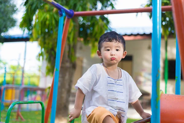 Young Asian boy play a iron train swinging at the playground und — Stock Photo, Image
