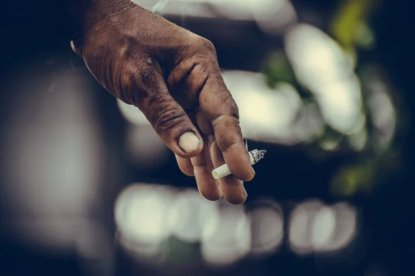 Крупним планом рука людини з цигаркою в його пальцях на зеленій спині — стокове фото
