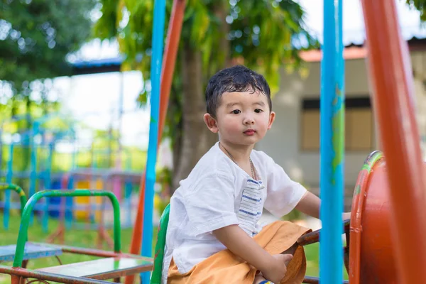 Genç Asyalı çocuk oyun bahçesi und sallanan bir demir tren
