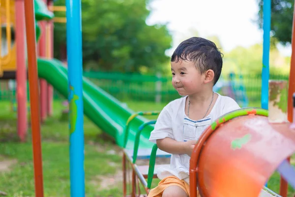 Young Asian boy play a iron train swinging at the playground und — Stock Photo, Image