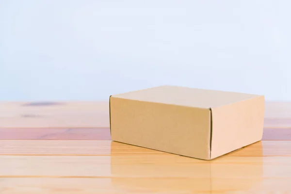 Caja de cartón marrón vacía sobre mesa de madera con espacio para copiar . — Foto de Stock