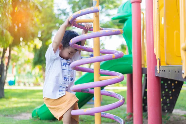 Okul bahçesinde bahar metal tırmanma oynayan etkin küçük çocuk