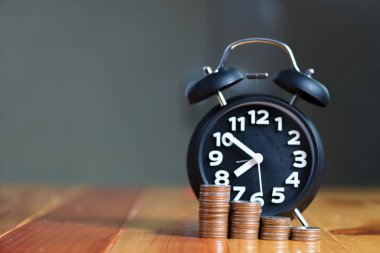 Çalar saat ve para yığınları adım çalışma masasında zaman için 
