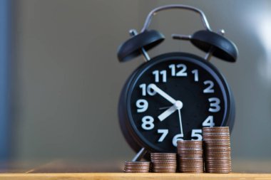Çalar saat ve para yığınları adım çalışma masasında zaman için 