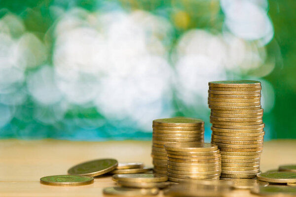 stacks of coins on table in garden with green background, financ