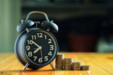 Çalar saat ve para yığınları adım çalışma masasında zaman için 