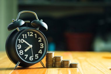 Çalar saat ve para yığınları adım çalışma masasında zaman için 