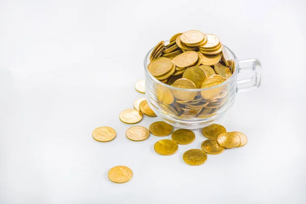 Moedas de ouro em um copo de café, no fundo branco . — Fotografia de Stock