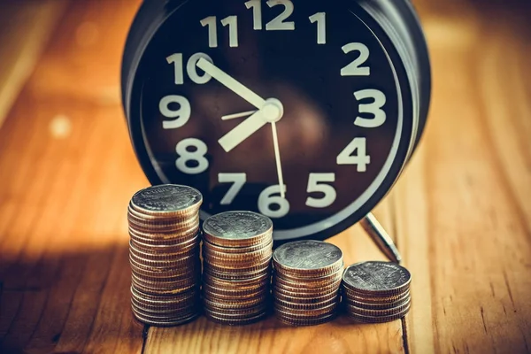 Reloj despertador y paso de las pilas de monedas en la mesa de trabajo, tiempo para — Foto de Stock