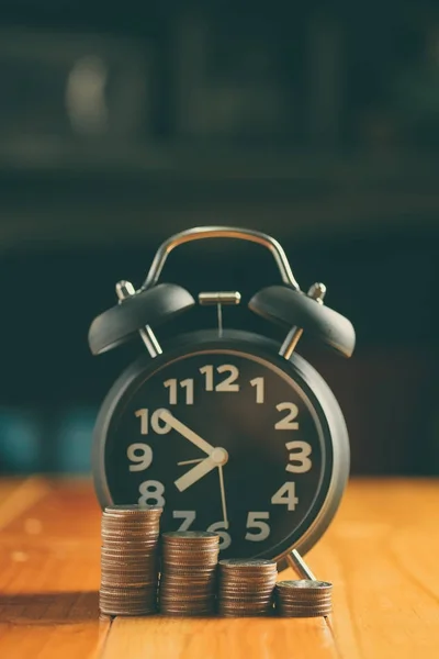 Годинник тривоги і крок монет стоїть на робочому столі, час — стокове фото