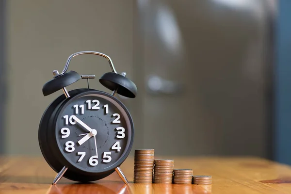 Reloj despertador y paso de las pilas de monedas en la mesa de trabajo, tiempo para — Foto de Stock