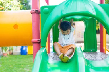Küçük Asyalı Çocuk Bahçesi sunli altında slayt oynayan