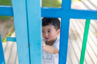 Üzgün Asyalı çocuk kaçmaya çalışırken ızgara arkasında. sığ Dof