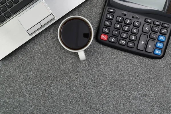 Laptop computer or notebook, calculator and cup of coffee on wor