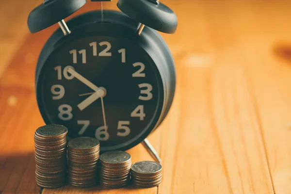 Relógio de alarme e passo de pilhas de moedas na mesa de trabalho, tempo para — Fotografia de Stock