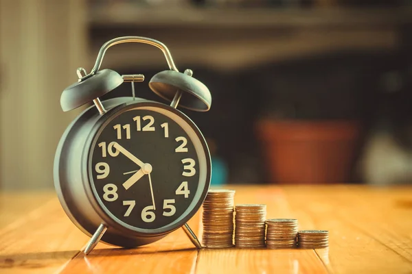 Reloj despertador y paso de las pilas de monedas en la mesa de trabajo, tiempo para — Foto de Stock