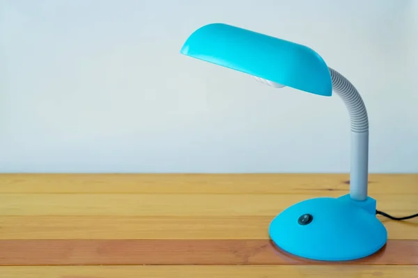 Blue desk lamp on wooden table with copy space.