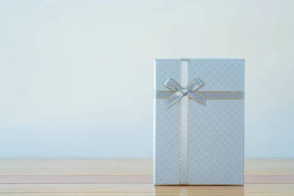 Blue white box with ribbon bow on wooden table with copy space f