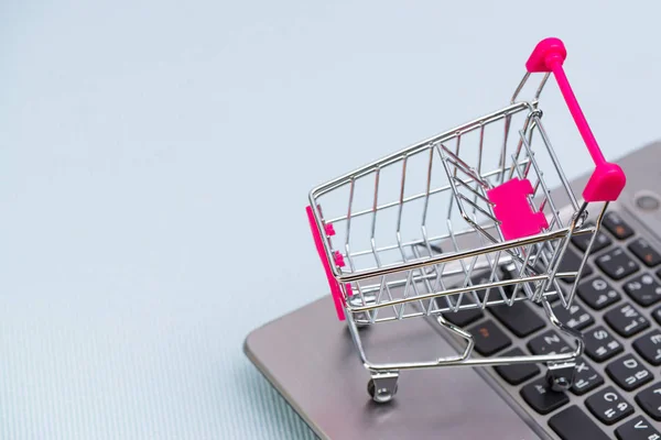 Shopping cart eller stormarknad vagn med laptop anteckningsboken på gre — Stockfoto