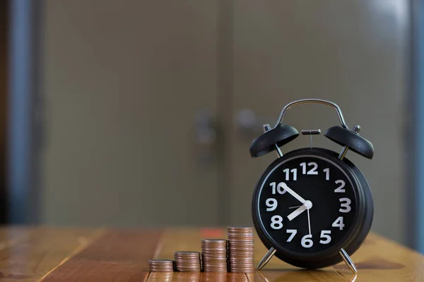 Reloj despertador y paso de las pilas de monedas en la mesa de trabajo, tiempo para — Foto de Stock